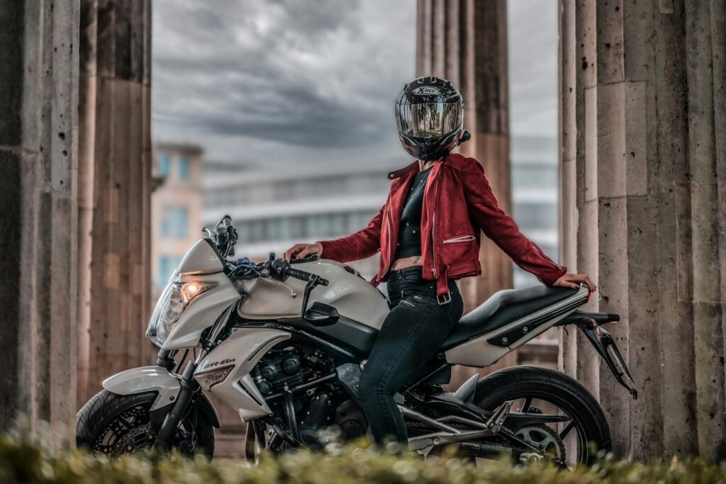 Photo by HUSQY _OFFICIAL a woman in a red jacket is sitting on a motorcycle