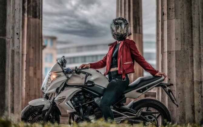 a woman in a red jacket is sitting on a motorcycle