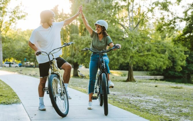 a man and a woman on bicycles giving each other a high five