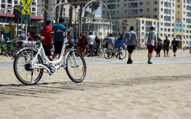 a white bike parked on top of a sandy beach